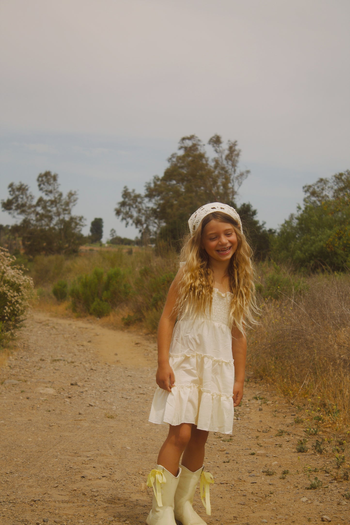 Toddler girl wearing yellow cowgirl boots with white bows and daisy accents – Safehaven Chasing Daisies collection