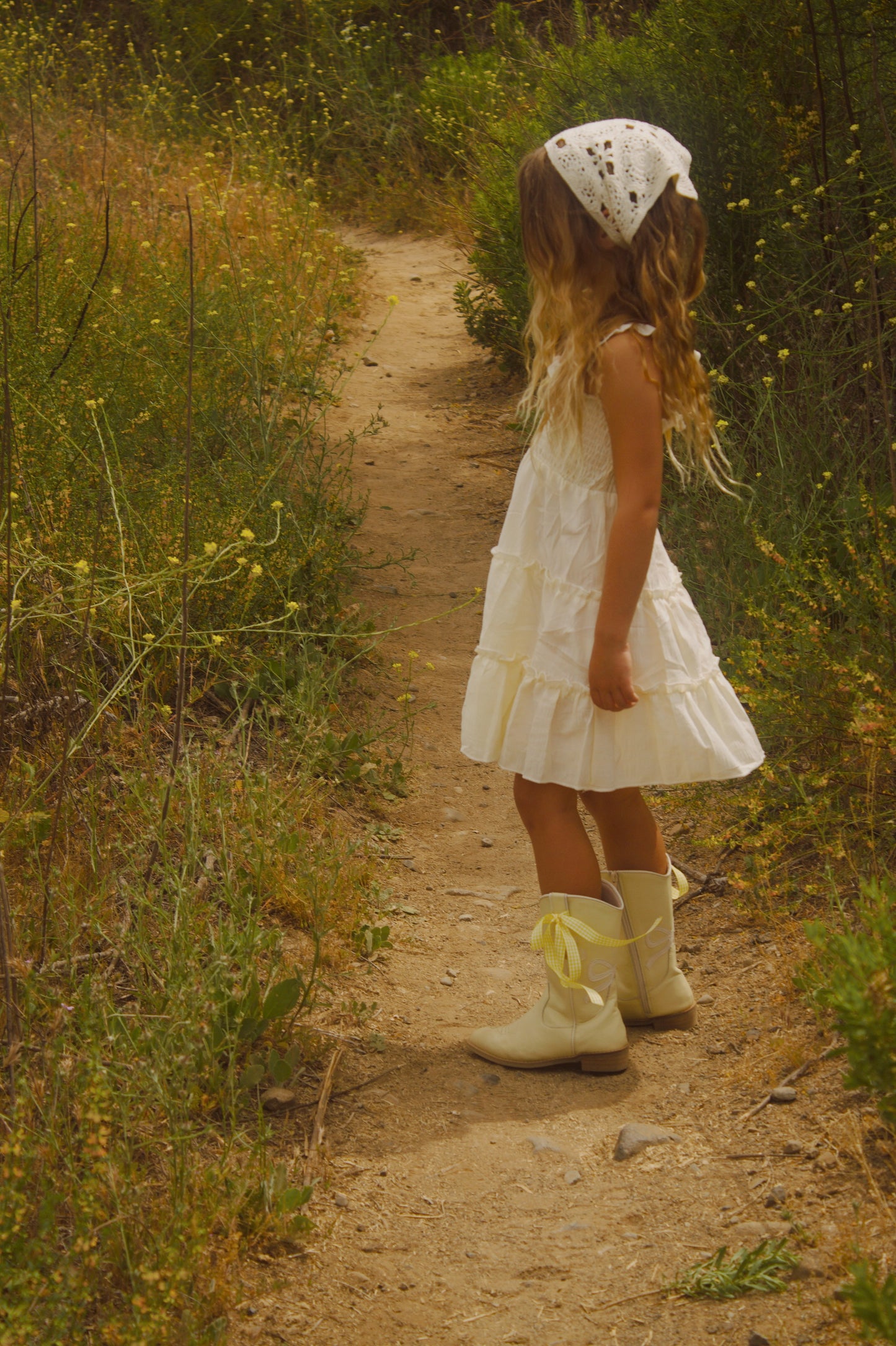 Toddler girl wearing yellow cowgirl boots with white bows and daisy accents – Safehaven Chasing Daisies collection cottage core aesthetic