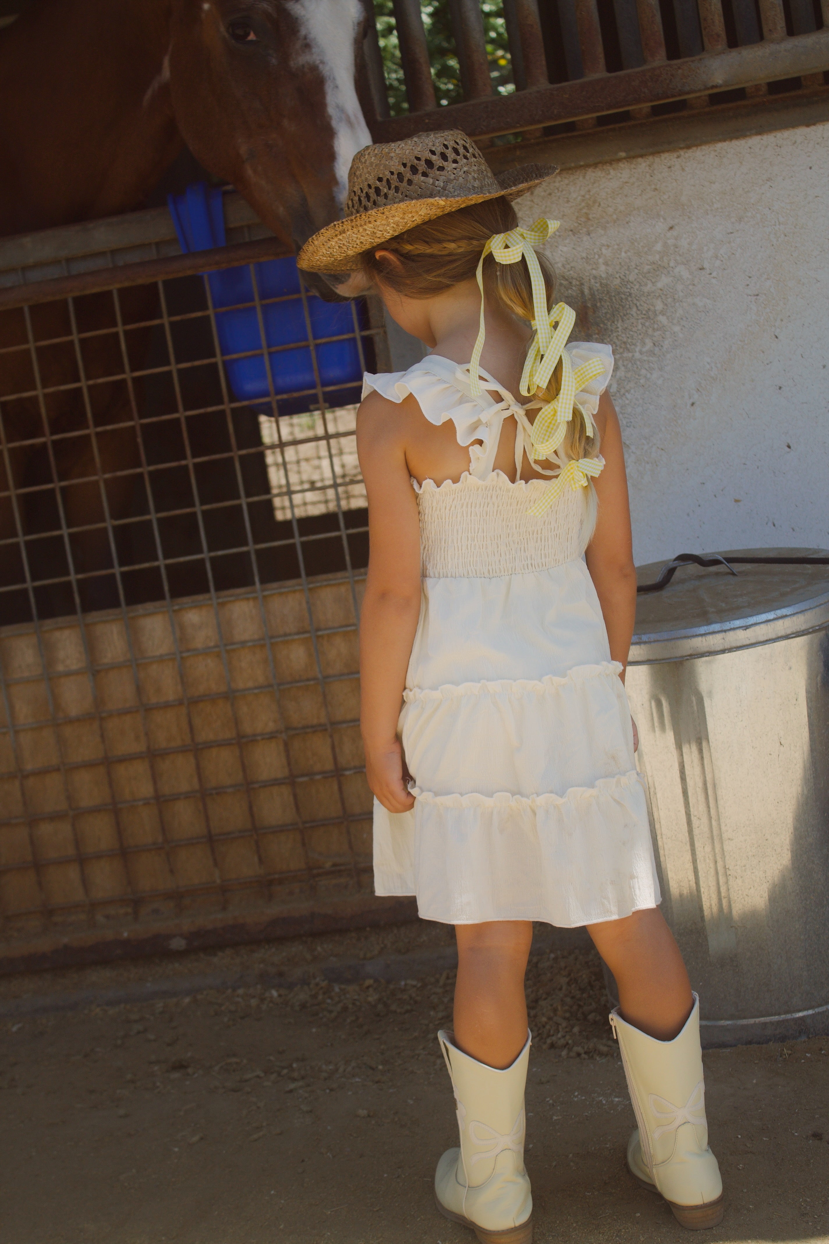 Little girl wearing a soft butter yellow cottagecore dress with flutter sleeves, posing outdoors in natural light. The dress has a vintage-inspired, dreamy feel—perfect for warm weather and whimsical adventures.