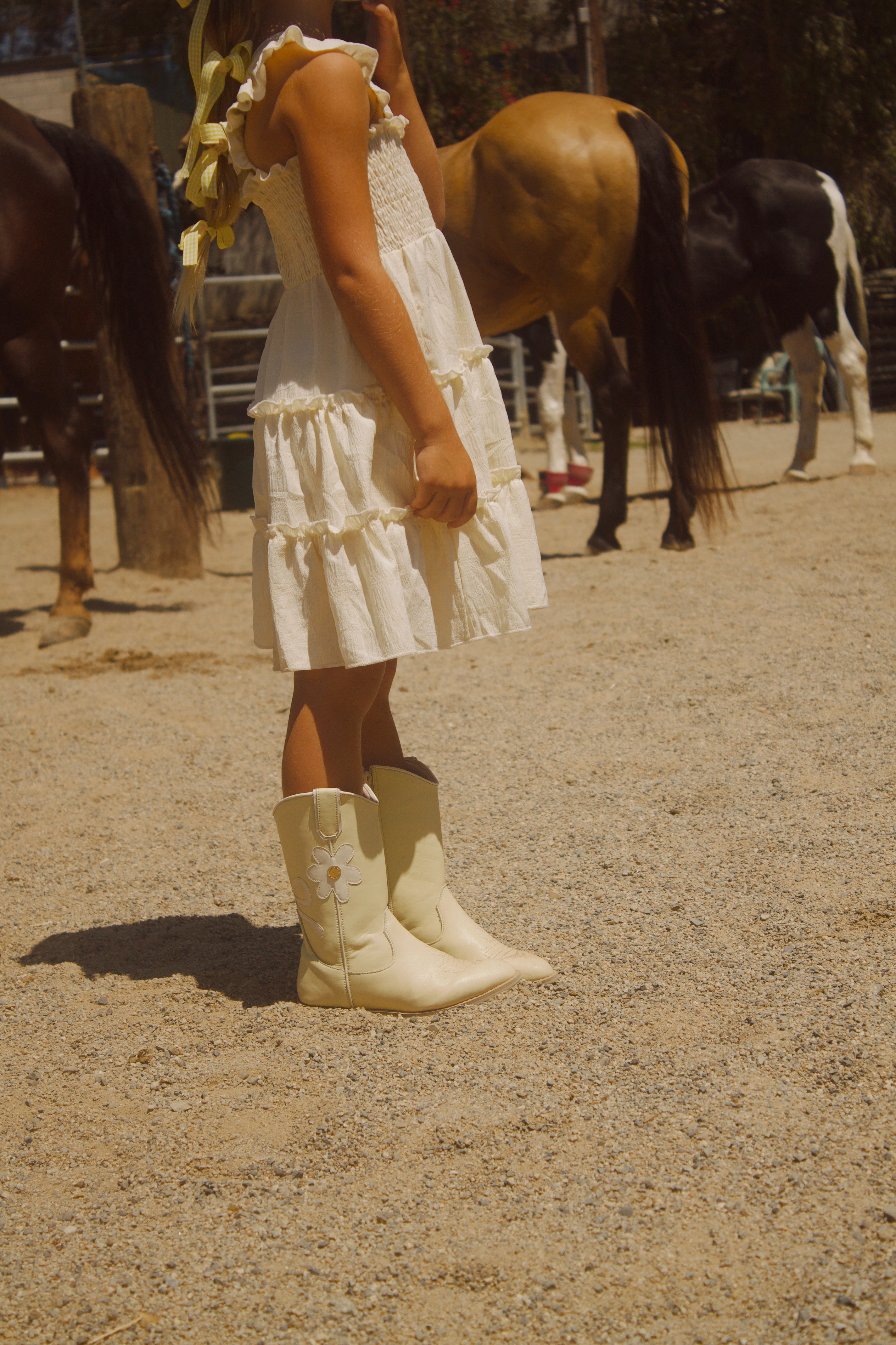 Toddler girl wearing yellow cowgirl boots with white bows and daisy accents – Safehaven Chasing Daisies collection